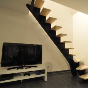 Escalier à limon central teinte noire – alliance du métal et du bois par Moreno Création. Escalier sur mesure à limon central avec quart tournant bas et limon noir effet acier fabriqué par Moreno Création à Louvres