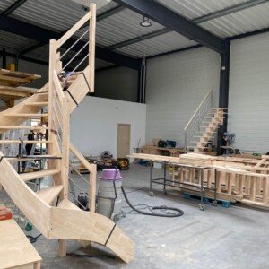 L’atelier Moreno Création à Chèvreville, où chaque escalier est conçu, façonné et assemblé à la main. Vue de l’atelier Moreno Création à Chèvreville, avec plusieurs escaliers en bois sur mesure en cours de fabrication artisanale.